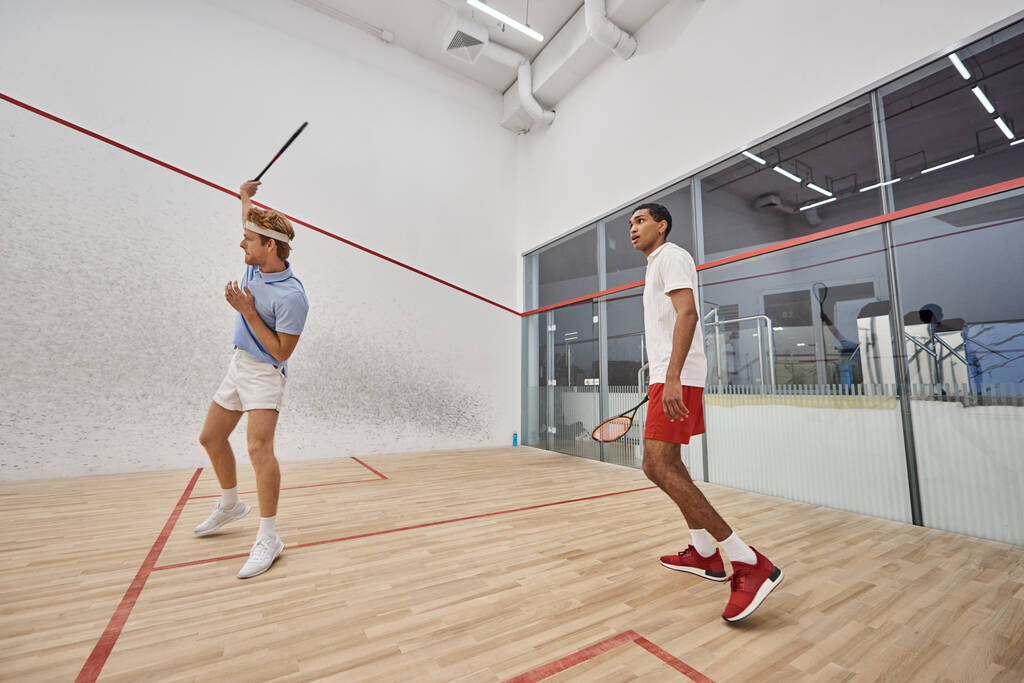 sporty interracial men in sportswear playing squash inside of court, challenge and motivation - Photo, Image