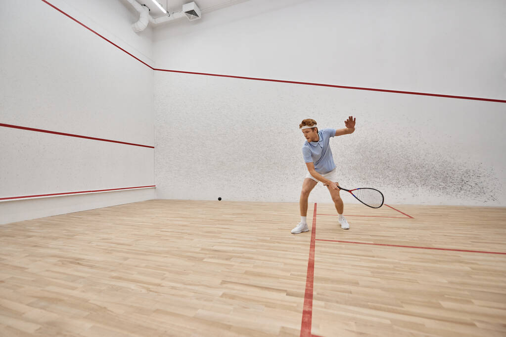 jovem e ativo ruiva homem em sportswear jogar squash dentro da corte, desafio e motivação - Foto, Imagem