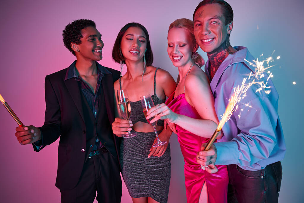Conceito de festa de Natal, amigos multiétnicos radiantes segurando sparklers e champanhe em roxo rosa - Foto, Imagem