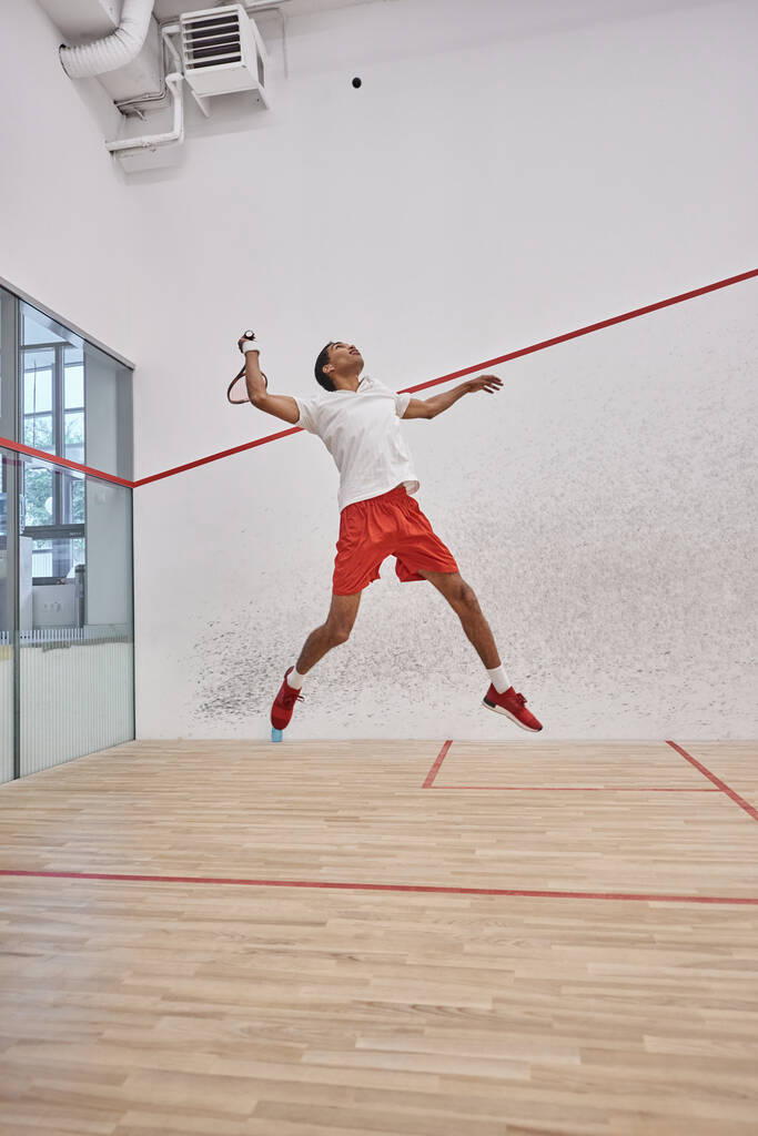 liike laukaus, energinen afrikkalainen pelaaja tilalla maila kun hyppäämällä ja pelaa squash - Valokuva, kuva