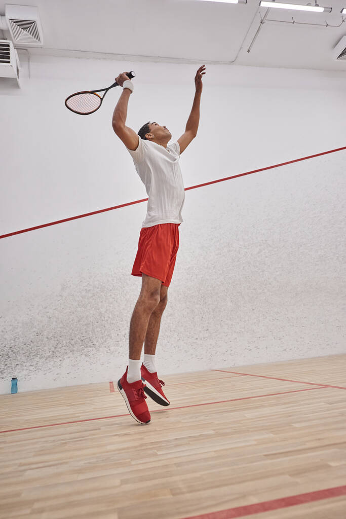 Bewegung, energische afrikanisch-amerikanische Mann hält Schläger beim Springen und Squash spielen, Training - Foto, Bild