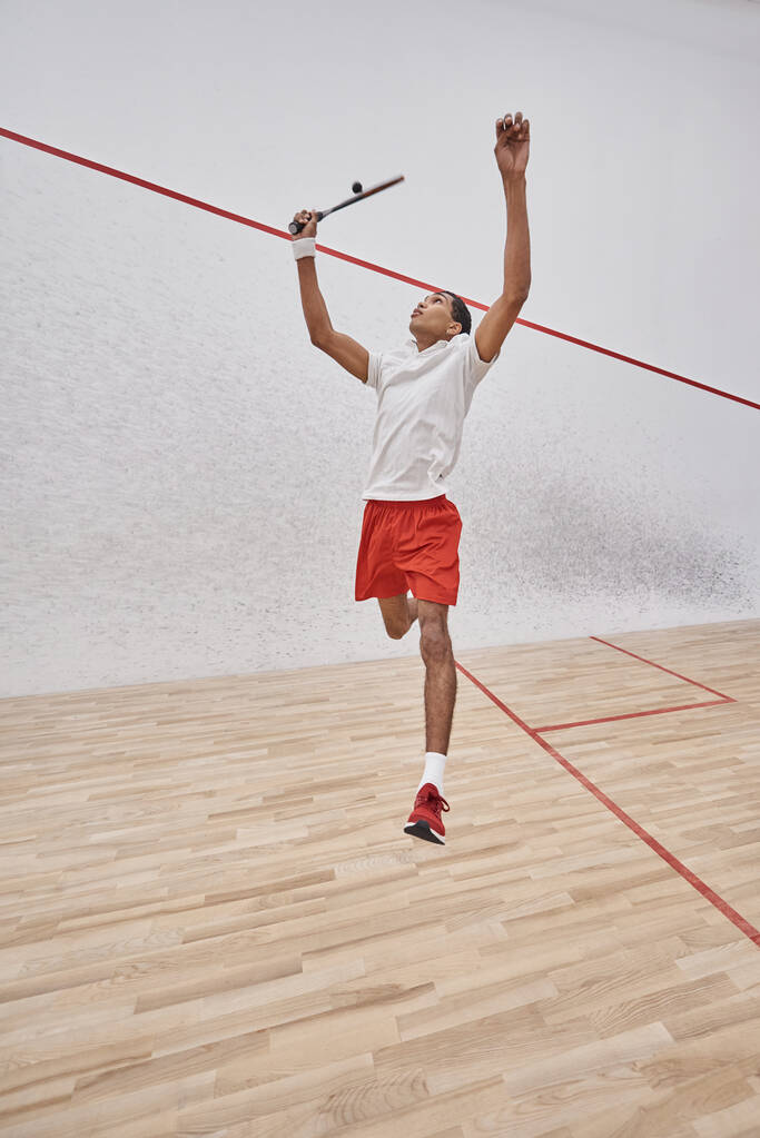 Bewegungsschuss, fokussierter afrikanisch-amerikanischer Sportler mit Schlägerspringen und Squash spielen vor Gericht - Foto, Bild