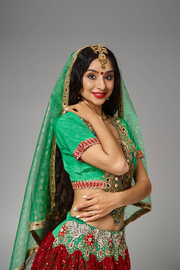 tiro vertical de la atractiva mujer india con el pelo largo y bindi punto sonriendo alegremente a la cámara - Foto, Imagen
