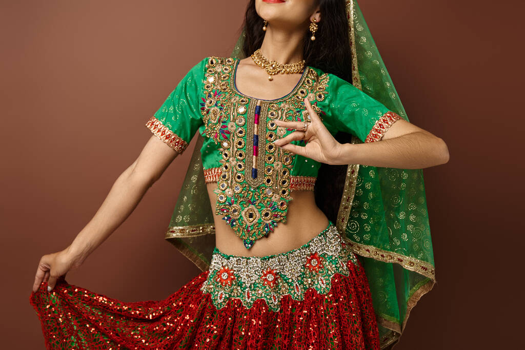 Kahverengi arka planda dans ederken milli giyinmiş genç Hintli kadının ellerine odaklan. - Fotoğraf, Görsel