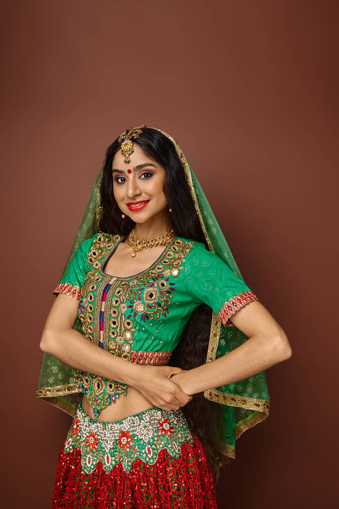 plan vertical de belle femme indienne aux cheveux longs et au voile vert souriant joyeusement à la caméra - Photo, image
