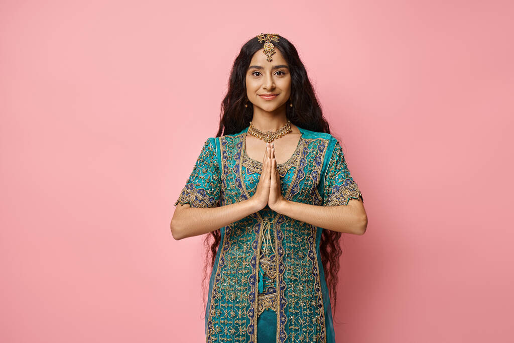 Ulusal kostümlü güzel Hintli kadın dua ediyor ve kameraya bakıyor. - Fotoğraf, Görsel