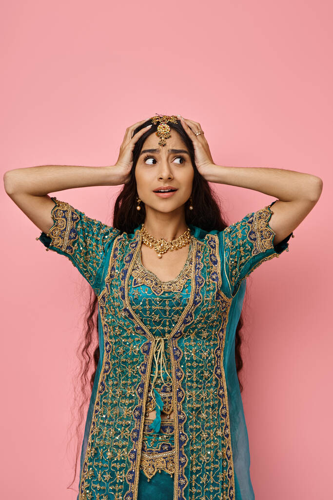 plan vertical de jeune femme indienne surprise en costume national posant les mains sur la tête - Photo, image