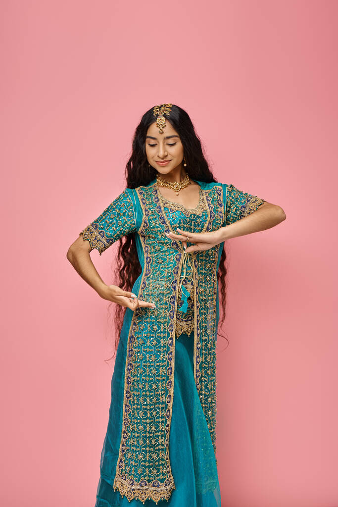 beau modèle indien féminin en costume national avec accessoires posant sur fond rose - Photo, image