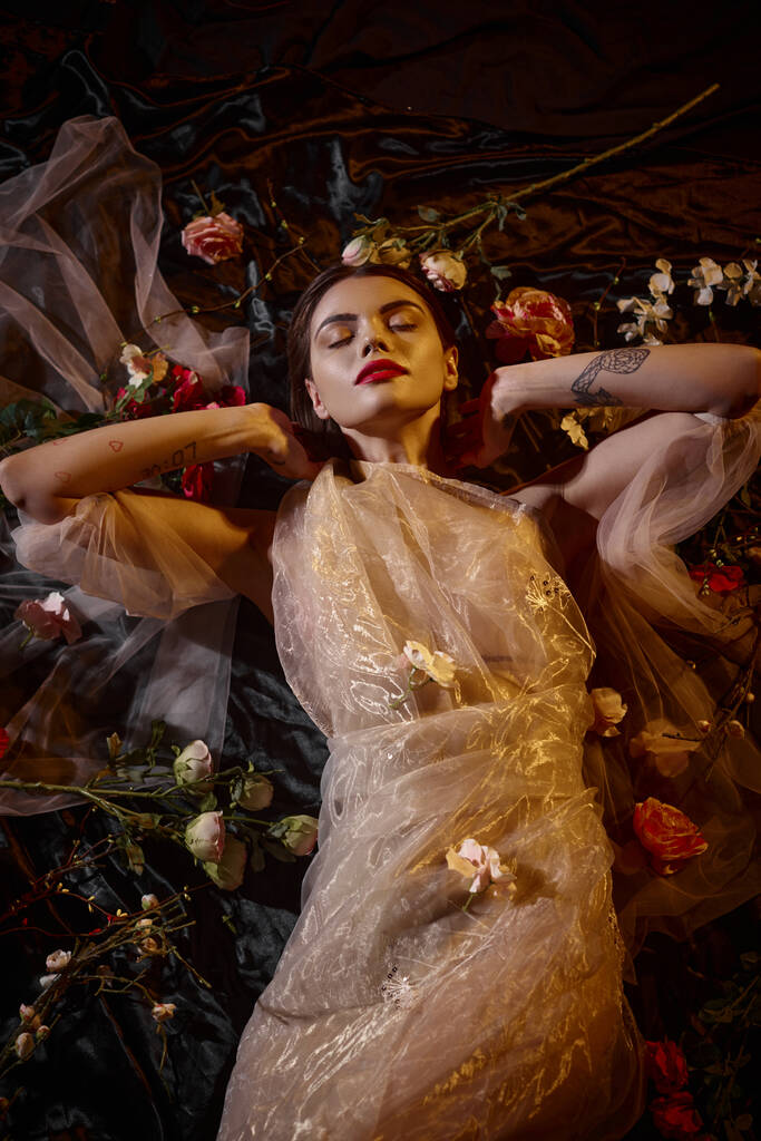 женская элегантность, чувственная молодая женщина в романтическом прозрачном платье, лежащем среди красивых цветов - Фото, изображение