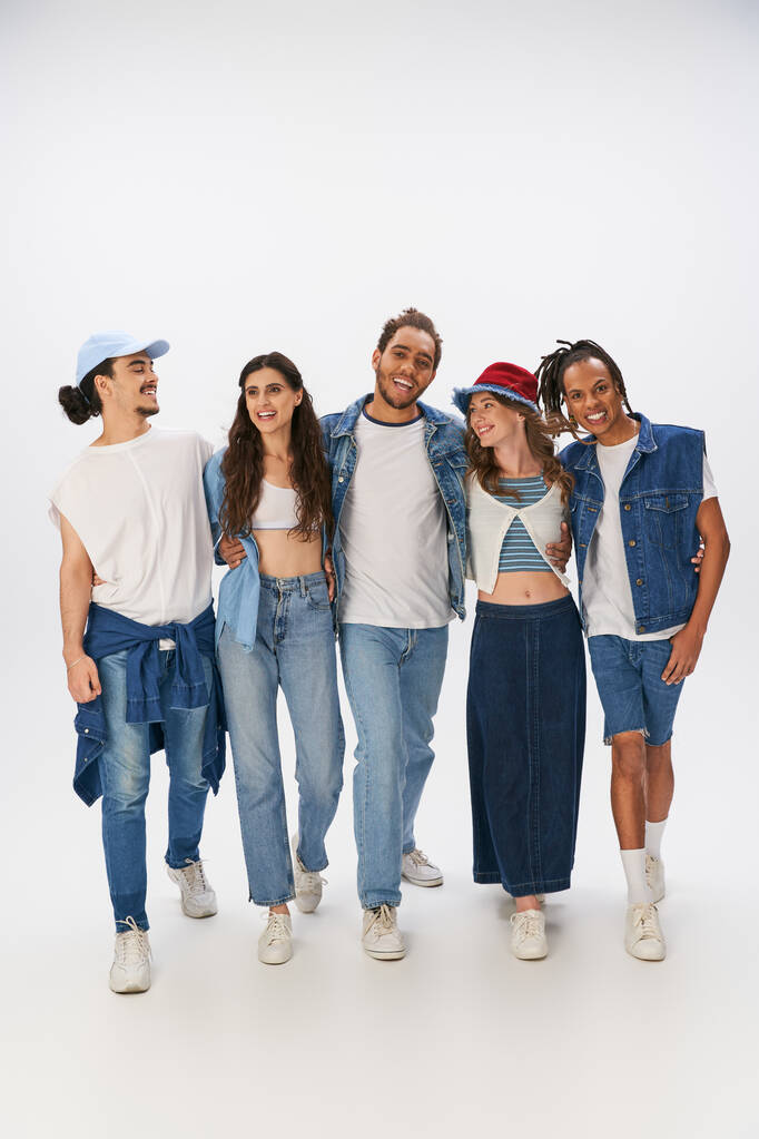різноманітна група радісних міжрасових друзів в модному вуличному одязі, що обіймає і ходить на сірому - Фото, зображення