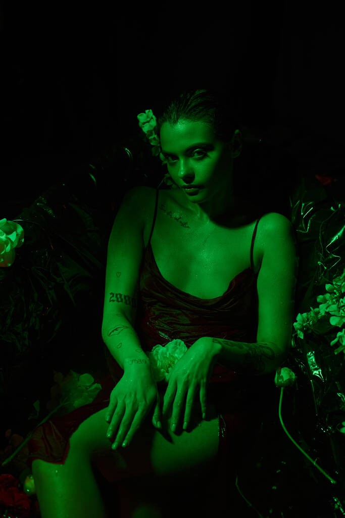 zelené světlo, horní pohled na krásnou mladou ženu s mokrými vlasy pózovat mezi květy ve vaně - Fotografie, Obrázek