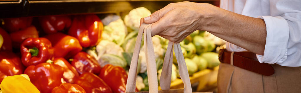 cropped view of mature female in casual attire holding shopping bag at grocery store, banner - Photo, Image