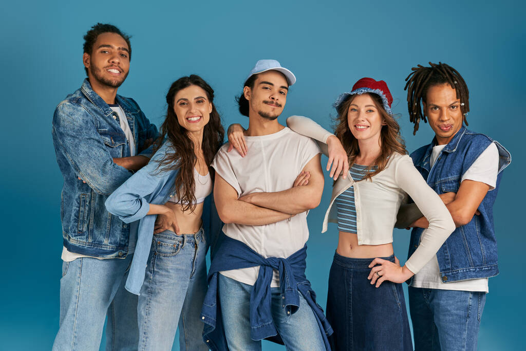 szczęśliwy wielokulturowy przyjaciele w casual strój patrząc w aparat na niebieski, różnorodność i moda - Zdjęcie, obraz