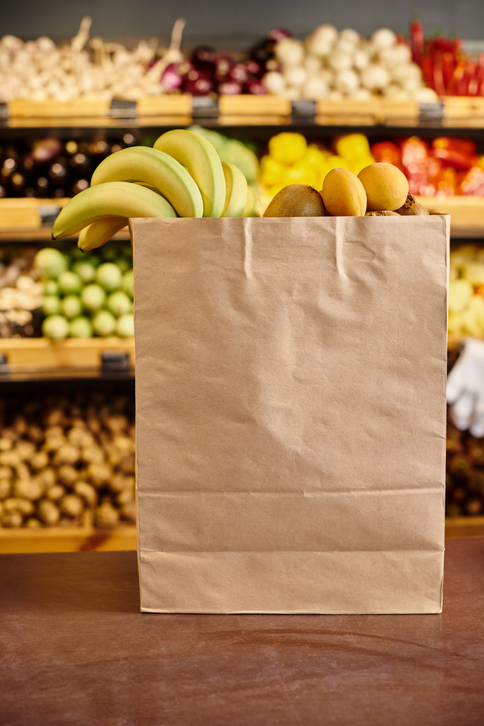 об'єкт фото величезної торгової сумки, наповненої свіжими натуральними фруктами з продуктовою стійкою на фоні - Фото, зображення