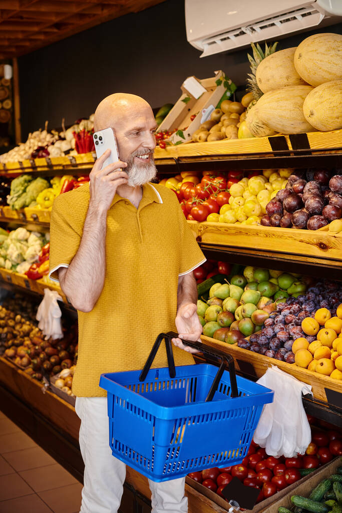 hyvännäköinen kypsä mies asiakas ostoskori puhuu puhelimitse valitessaan ostoksia - Valokuva, kuva