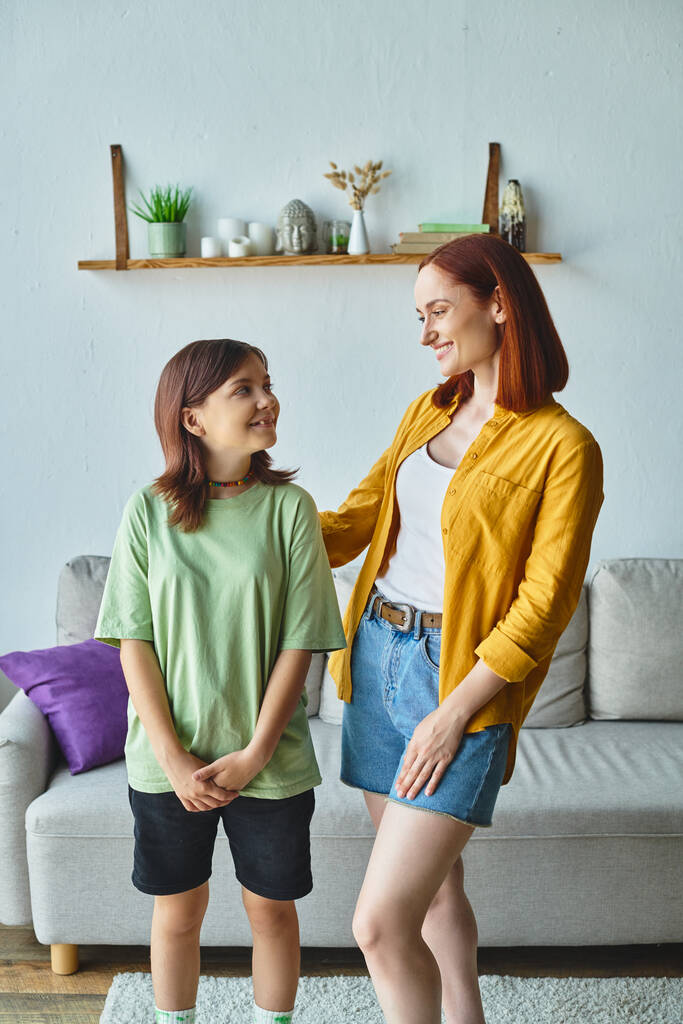 glückliche Mutter und Teenager-Tochter lächeln sich zu Hause im Wohnzimmer an, Liebe und Fürsorge - Foto, Bild