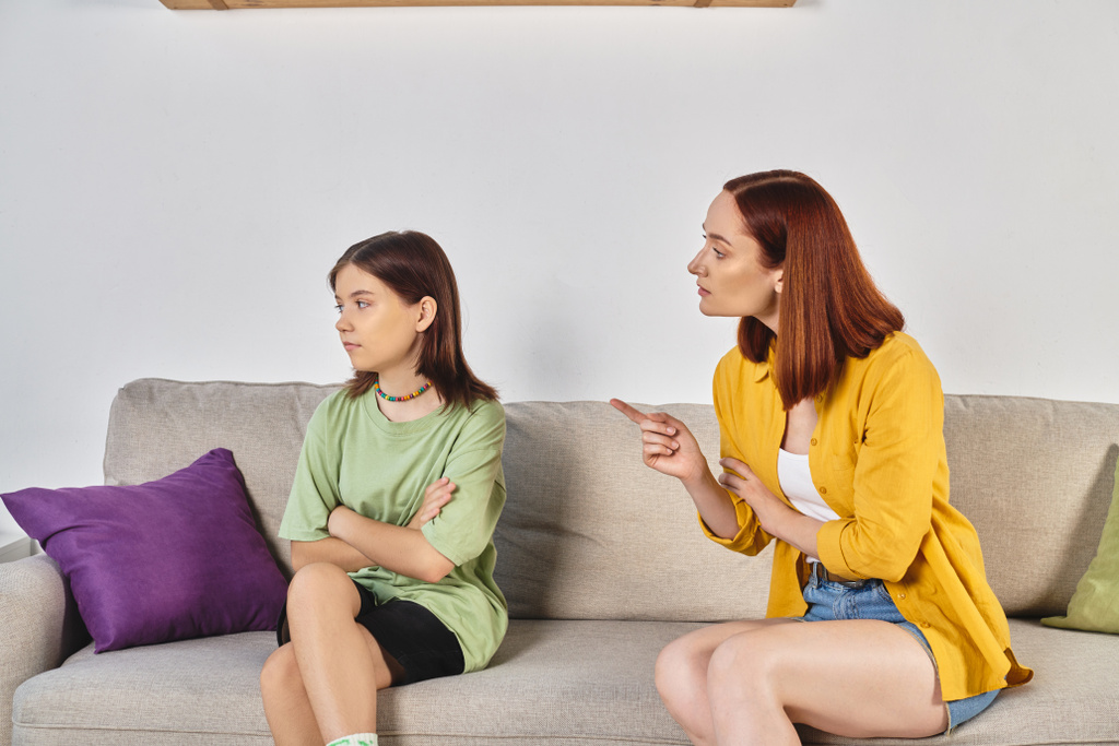 vakava puhua, tiukka äiti osoittaa turhautunut teini tytär istuu sohvalla olohuoneessa - Valokuva, kuva