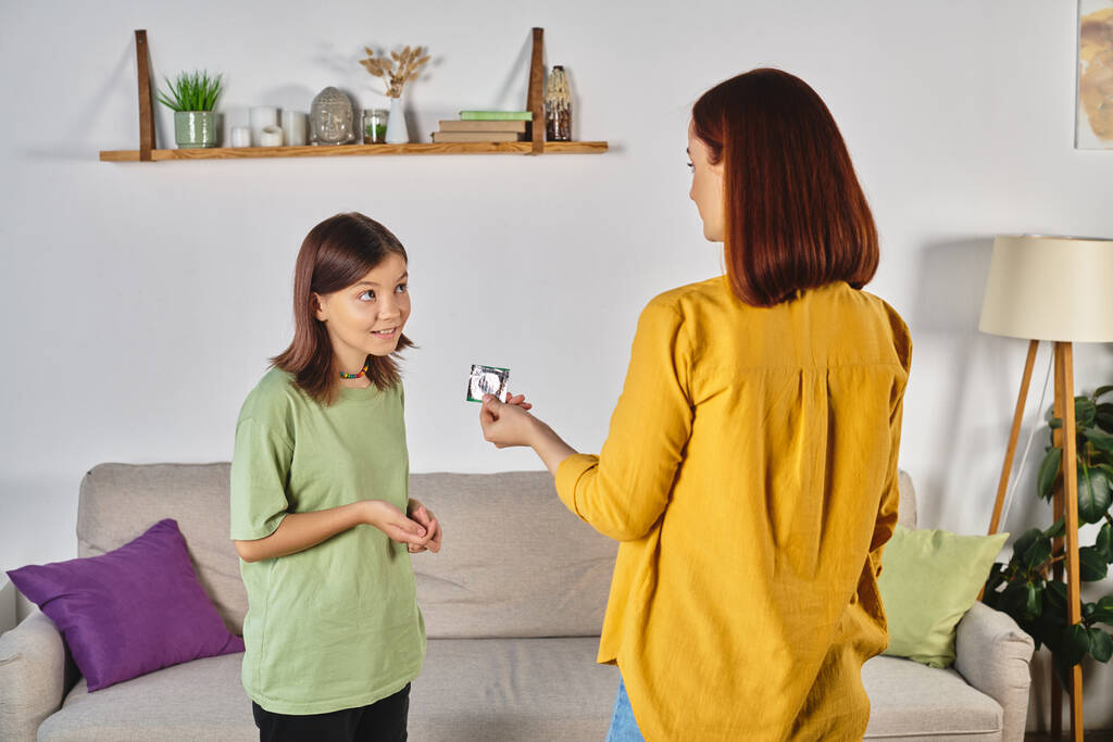 Anne evde konuşurken kafası karışık genç kıza prezervatif gösteriyor, cinsel eğitim. - Fotoğraf, Görsel