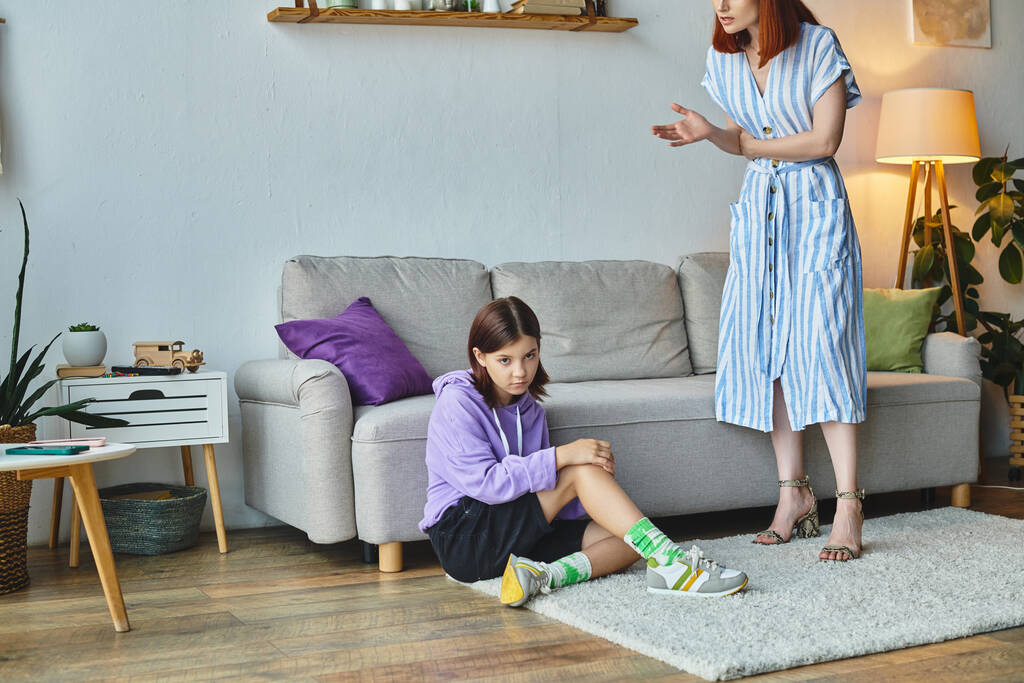 vážná žena mluví k frustrované dospívající dceři sedí na podlaze v obývacím pokoji, generace mezera - Fotografie, Obrázek