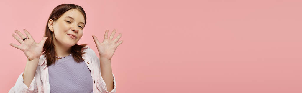 alegre adolescente en elegante ropa casual agitando las manos y mirando a la cámara en rosa, pancarta - Foto, Imagen