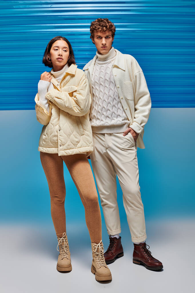 divatos férfi kéz a zsebben közel ázsiai nő meleg ruhát kék háttér műanyag panel - Fotó, kép