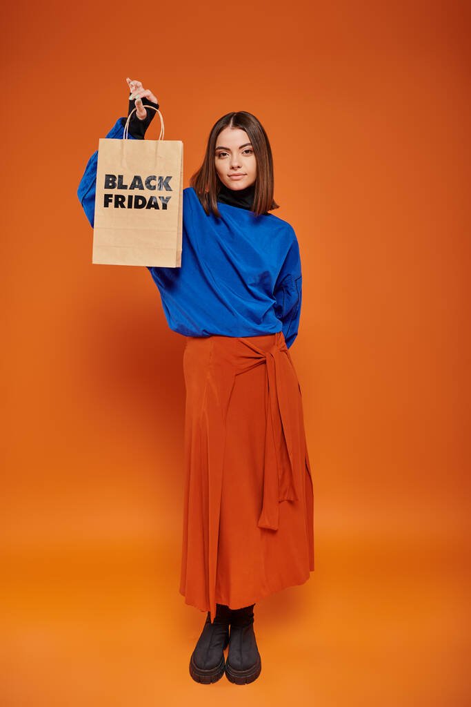 giovane donna alla moda in abbigliamento autunnale e stivali con borsa della spesa con lettere nere venerdì - Foto, immagini