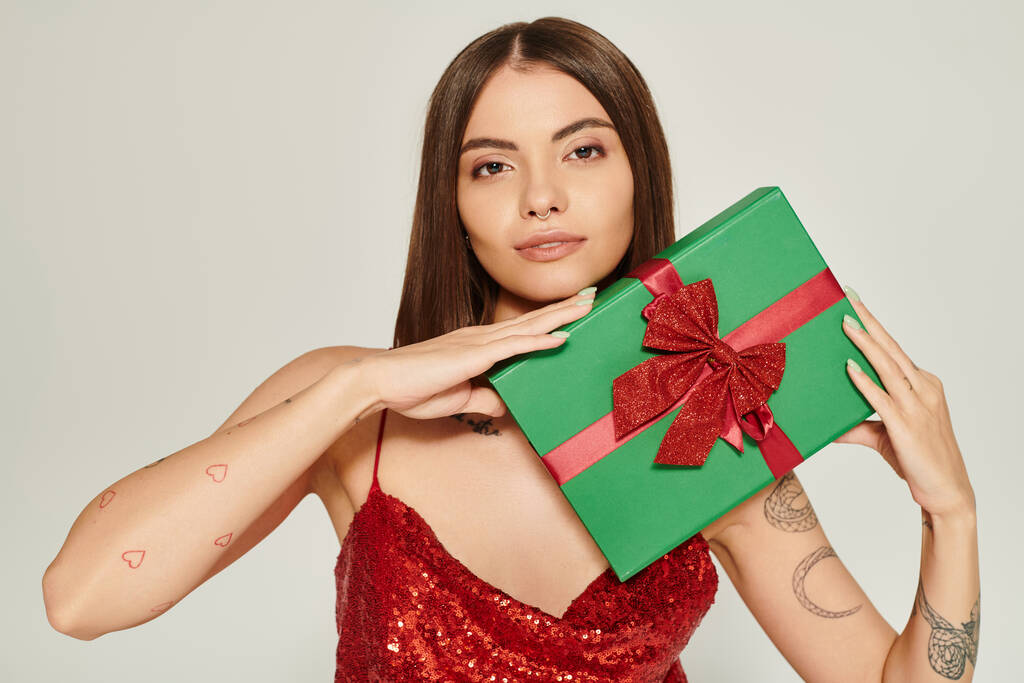 krásná žena s piercing a tetování s dárkem v ruce při pohledu do kamery, vánoční dárky - Fotografie, Obrázek