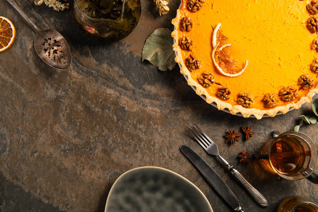 composizione del Ringraziamento, torta di zucca guarnita vicino a posate vintage, spezie e tè sul tavolo di pietra - Foto, immagini
