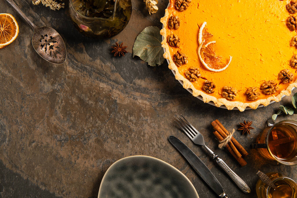 День благодарения натюрморт, тыквенный пирог возле винтажных столовых приборов, горячий чай и корица на каменной поверхности - Фото, изображение