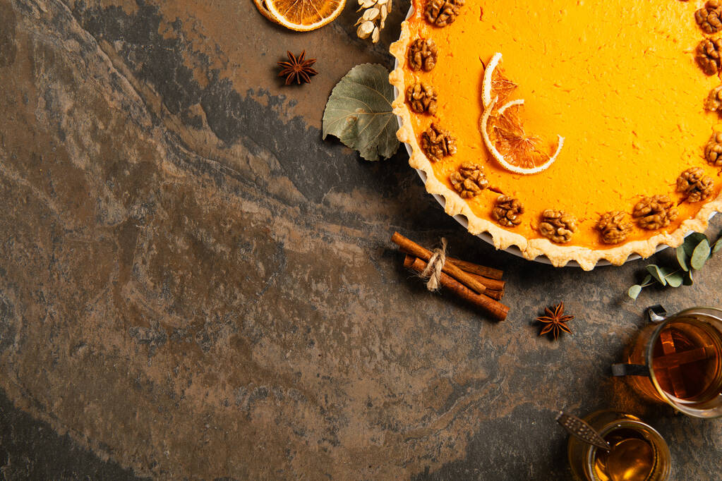 День благодарения фон, тыквенный пирог с грецкими орехами и апельсиновыми ломтиками рядом с корицей палочки и теплый чай - Фото, изображение