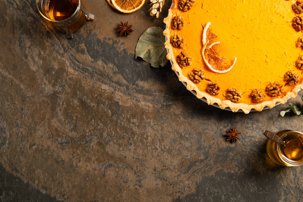 herkullinen kurpitsapiirakka saksanpähkinöillä ja appelsiiniviipaleilla lähellä lämmintä teetä, syksyn kiitospäivä asetelma - Valokuva, kuva