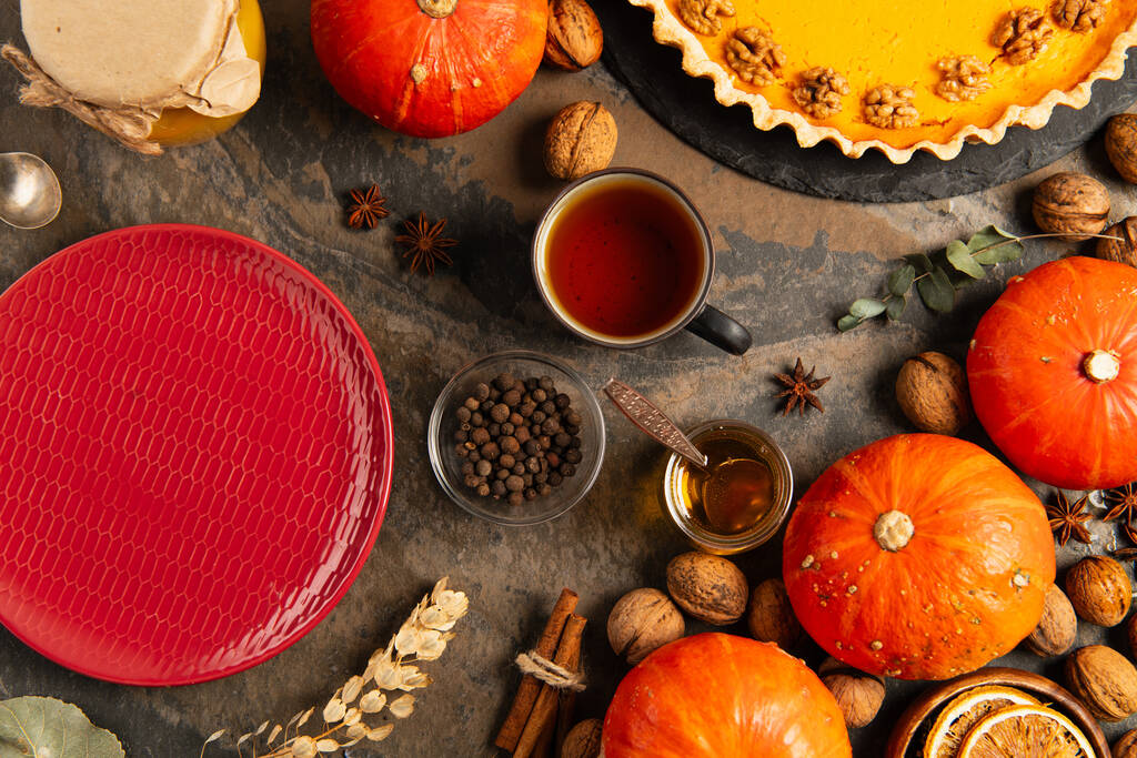 dankzegging kleurrijke herfst objecten, rode keramische plaat in de buurt van oranje kalebassen en pompoentaart - Foto, afbeelding