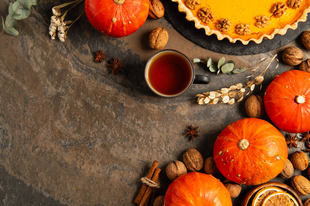 warm tea near thanksgiving pumpkin pie and ripe gourds on stone tabletop with spices and herbs - Photo, Image