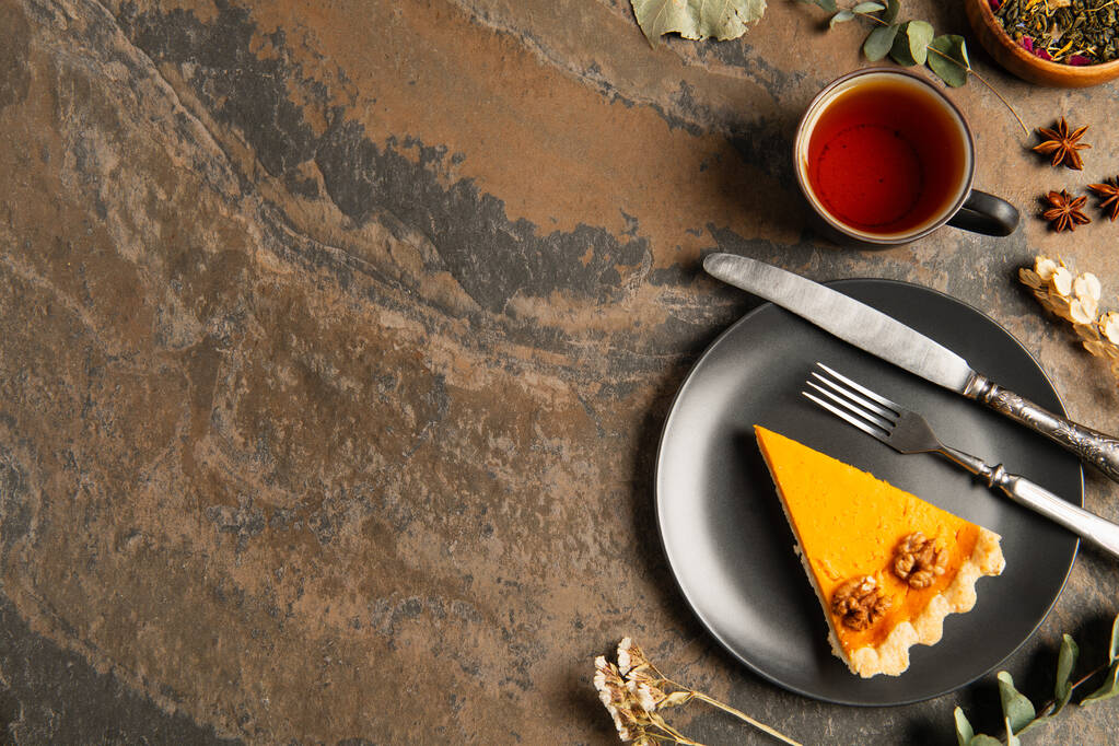 thanksgiving concept, pumpkin pie and cutlery near warm tea and aromatic herbs on stone surface - Photo, Image