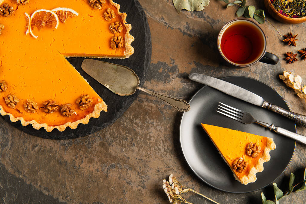 tarte à la citrouille thanksgiving aux noix et tranches d'orange près de couverts vintage sur table en pierre rustique - Photo, image