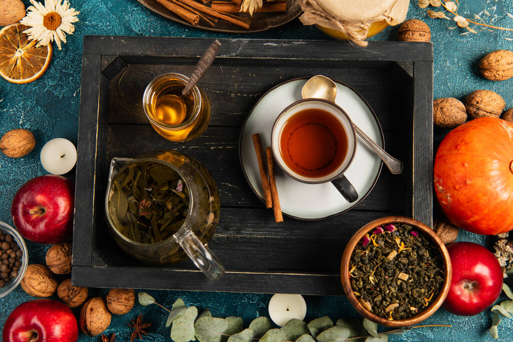 έννοια ευχαριστιών, μαύρο ξύλινο δίσκο με τσάι από βότανα και μέλι κοντά σε πολύχρωμα αντικείμενα συγκομιδής - Φωτογραφία, εικόνα