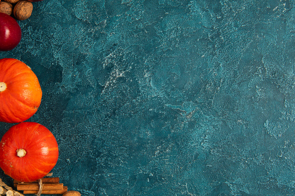 ώριμες κολοκύθες πορτοκαλιού κοντά σε ξυλάκια κανέλας και μήλο σε μπλε υφή φόντο, ρύθμιση Ευχαριστιών - Φωτογραφία, εικόνα