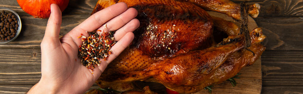 délicieux dîner de thanksgiving, vue recadrée de l'homme tenant des épices près de la dinde grillée, bannière - Photo, image