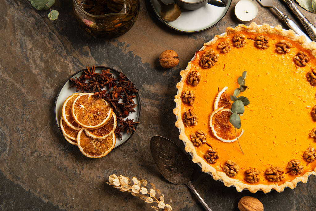 mesa de pedra com decoração festiva de ação de graças e deliciosa torta de abóbora com nozes e fatias de laranja - Foto, Imagem