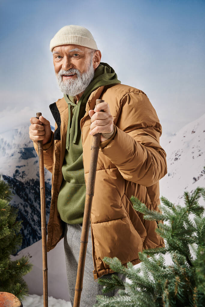 Père Noël athlétique en tenue chaleureuse et confortable debout sur les skis et souriant à la caméra, concept de Noël - Photo, image