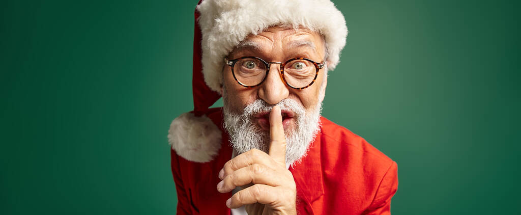 елегантний чоловік, одягнений як Санта, показує жест мовчання і дивиться на камеру, зимова концепція, банер - Фото, зображення