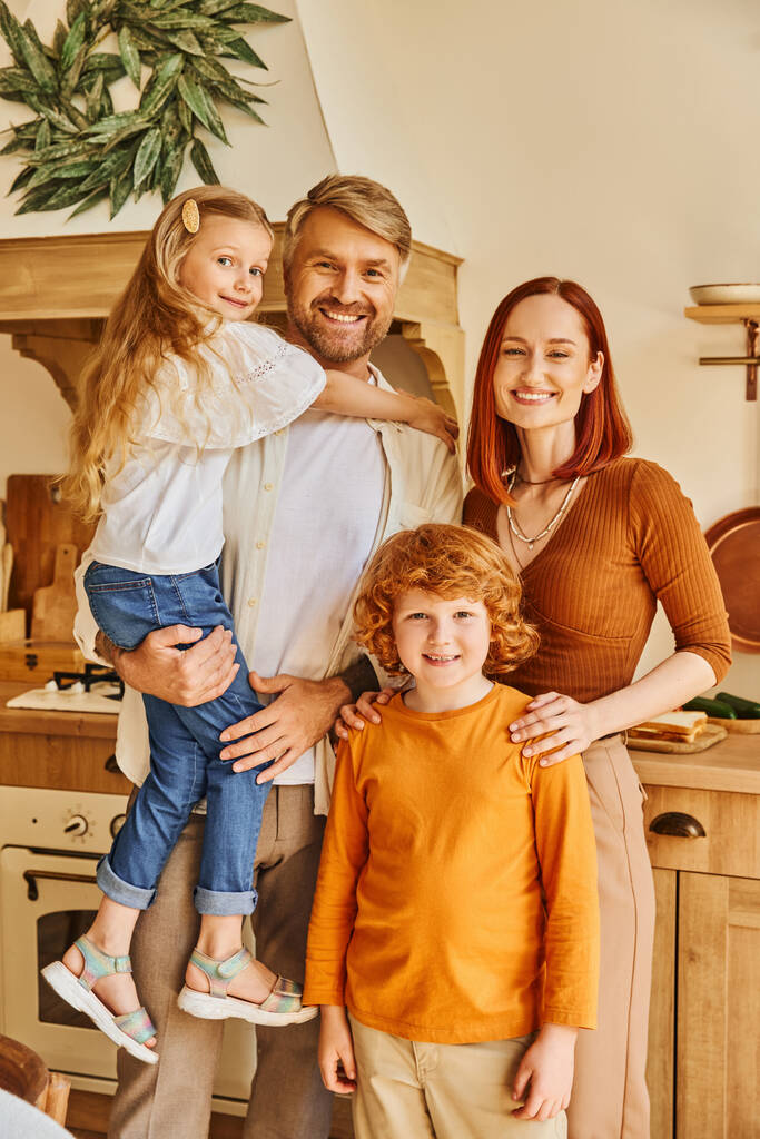 enfants gais avec des parents souriants regardant la caméra dans la cuisine moderne, environnement confortable à la maison - Photo, image