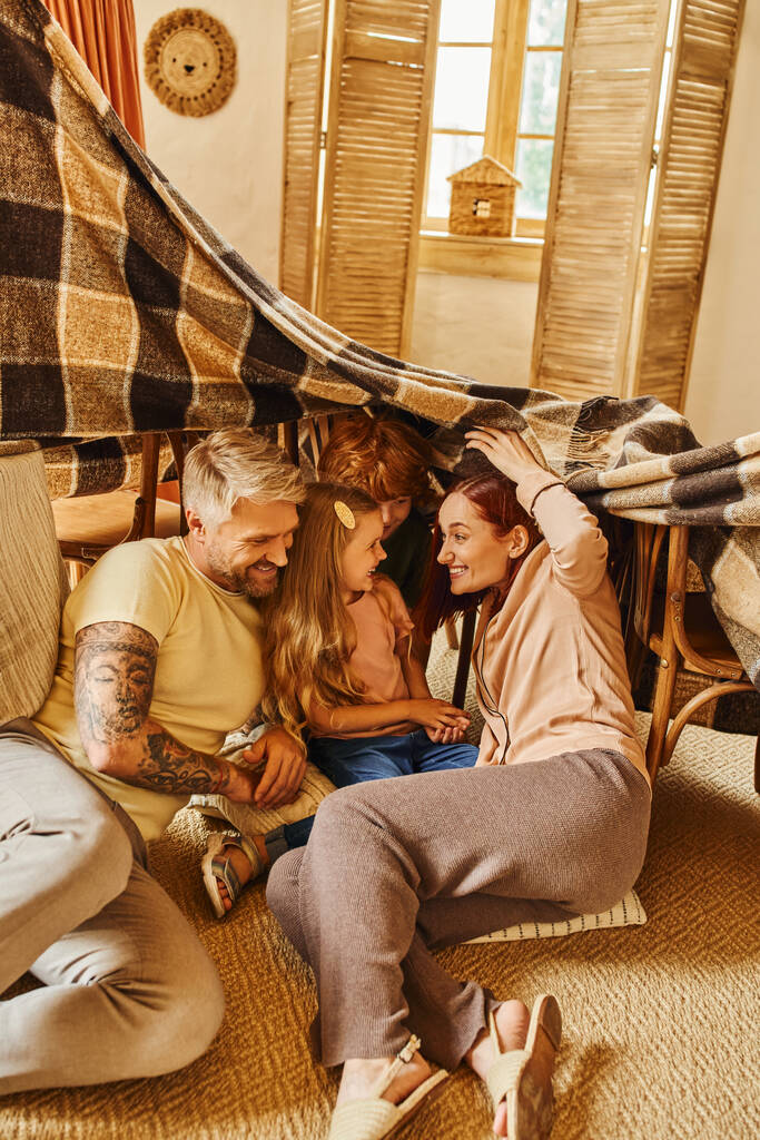 gelukkige kinderen met ouders spelen onder deken hut in woonkamer thuis, emotionele verbinding - Foto, afbeelding