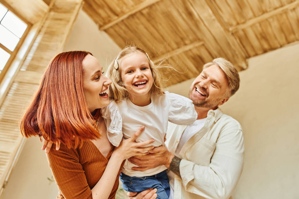 glückliche Eltern spielen mit überglücklicher Tochter im Wohnzimmer zu Hause, verbindende Momente - Foto, Bild