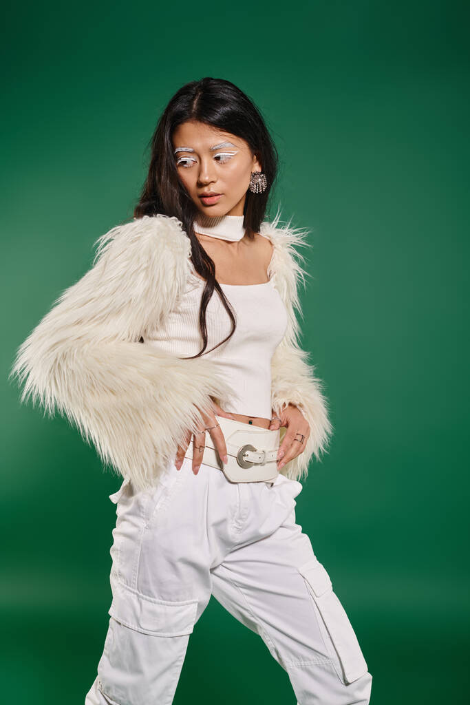ázsiai barna nő -ban teljes fehér ruha és smink pózol zöld háttér, téli divat - Fotó, kép