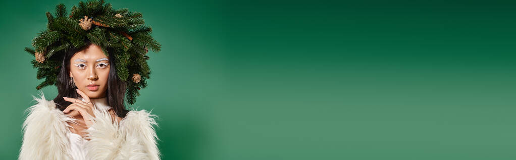 sztandar kobiety w sztucznym futrze i naturalny wieniec na głowie patrząc na kamerę na zielonym tle - Zdjęcie, obraz