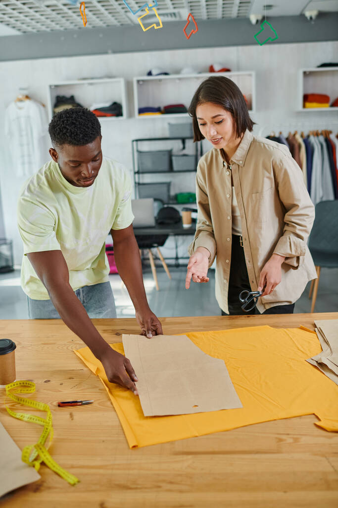 luova monikulttuurinen vaatteet suunnittelijat työskentelevät ompelu malleja moderni painettu studio - Valokuva, kuva