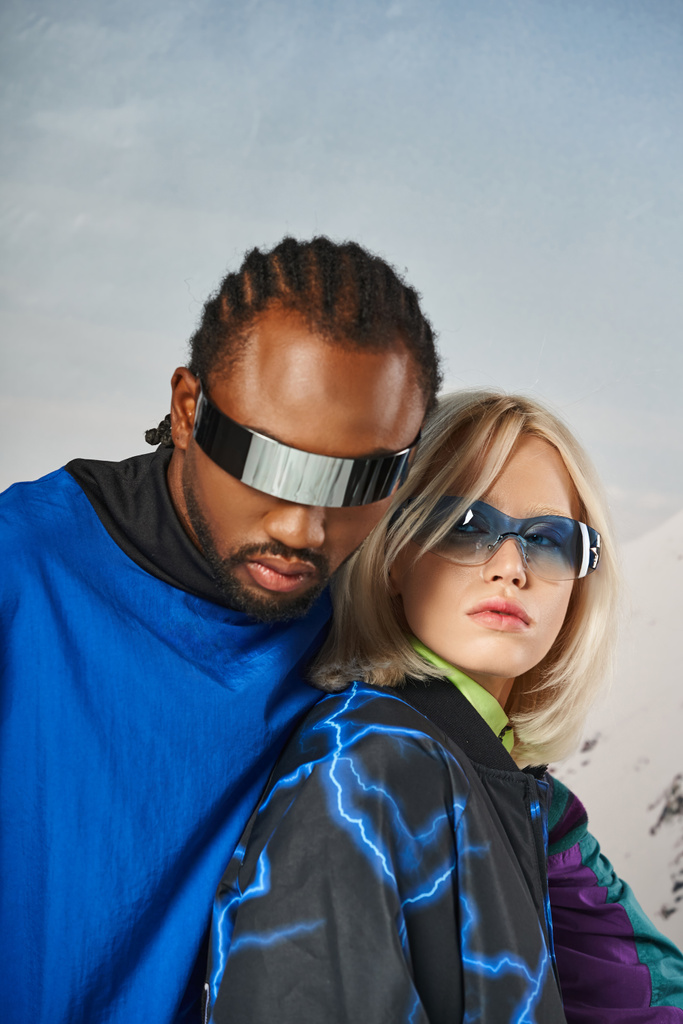 zblízka stylového páru v zářivých slunečních brýlích objímání a pohled na fotoaparát, zimní koncept - Fotografie, Obrázek