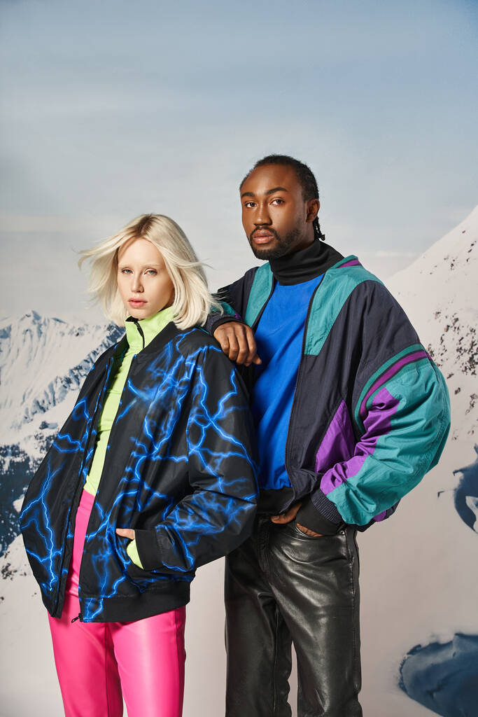 atraktivní mladý mezirasový pár v teplém stylovém oblečení při pohledu na kameru, zimní koncept - Fotografie, Obrázek