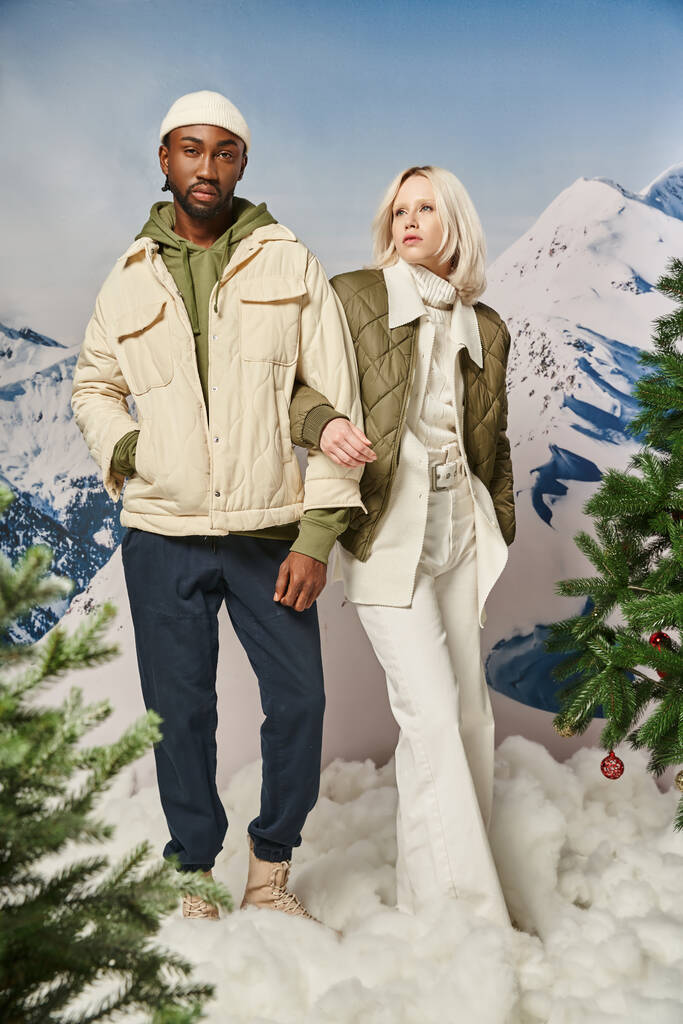 schönes multikulturelles Paar in warmer stylischer Kleidung posiert mit Hand auf Arm, Winterkonzept - Foto, Bild